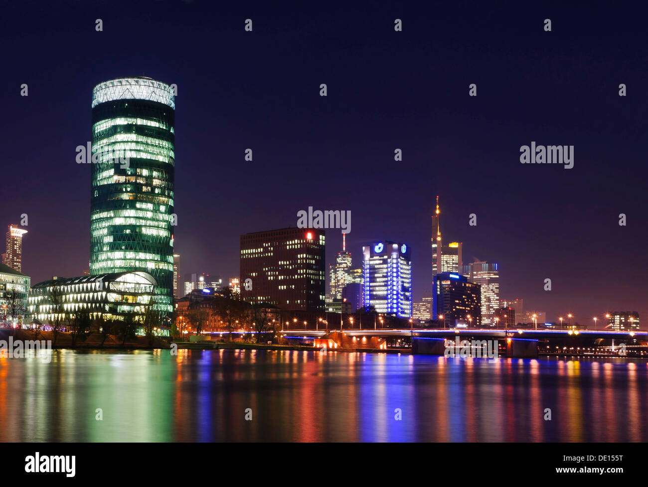 Skyline di Francoforte con Westhafen Tower e ponte Friedensbruecke da sud-ovest della riva del fiume principale di notte Foto Stock