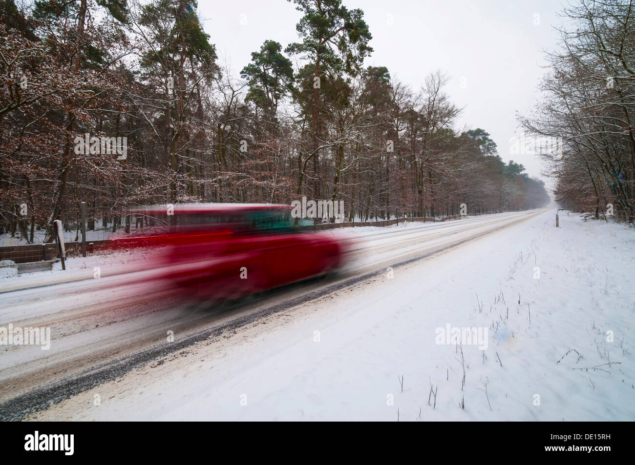 Coperte di neve strada in inverno con una vettura veloce passando, Mörfelden, Hesse, Germania Foto Stock