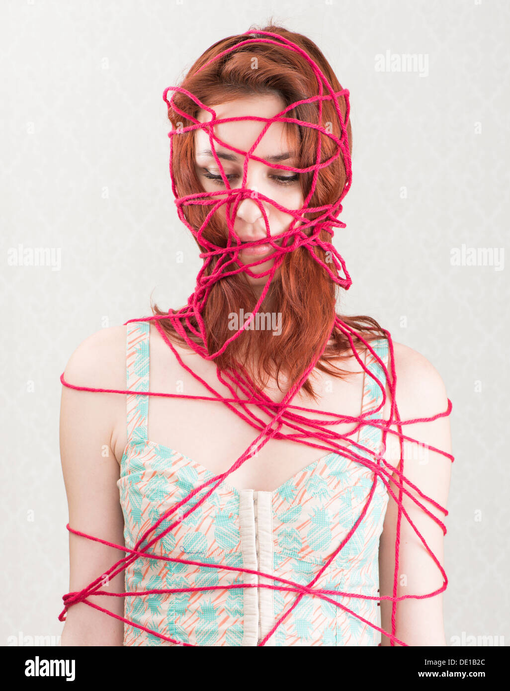 Immagine concettuale della donna intrappolata e vincolato con il rosso di filati di cotone Foto Stock