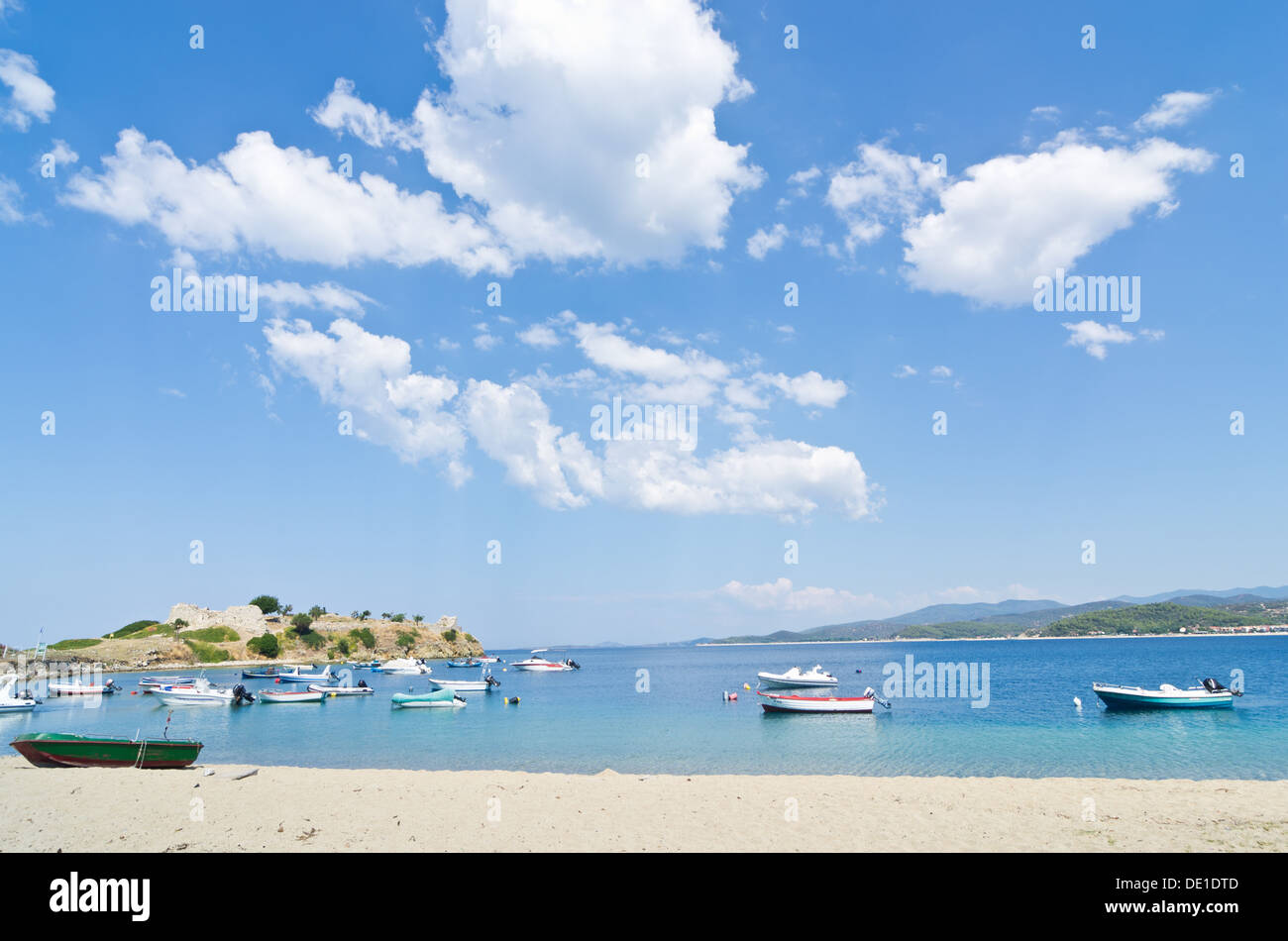 Sotto il perfetto nuvole, barche in un piccolo porto di pescatori sulla spiaggia in Grecia Foto Stock