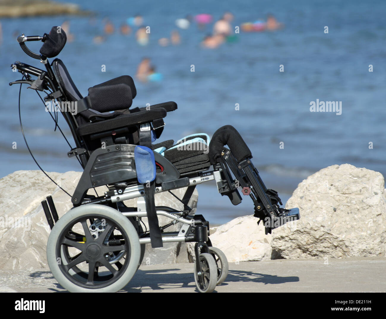 Nuova sedia a rotelle per disabili sul pontile di rocce in riva al mare Foto Stock