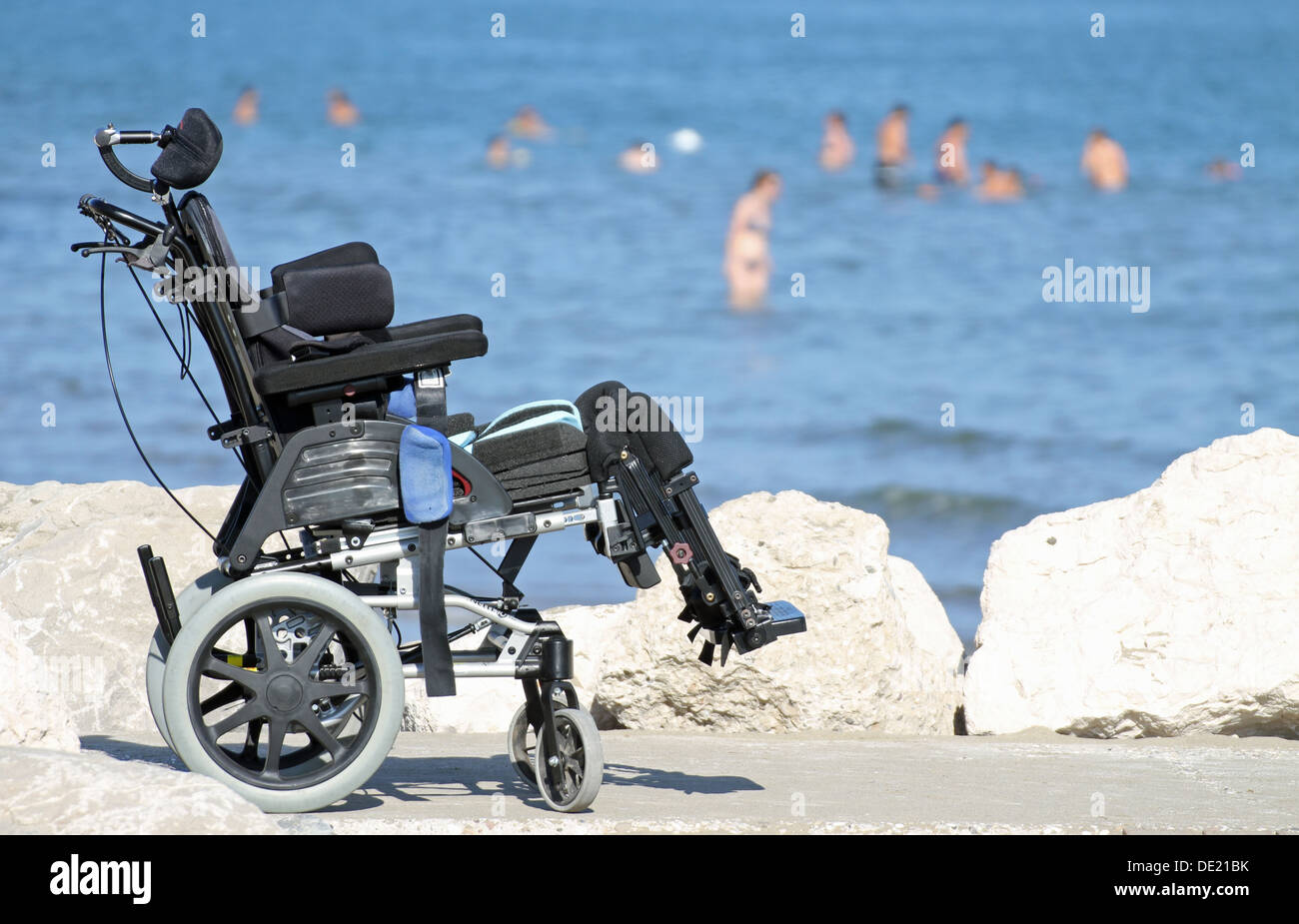 Nuova sedia a rotelle per disabili sul pontile di rocce di mare in estate Foto Stock