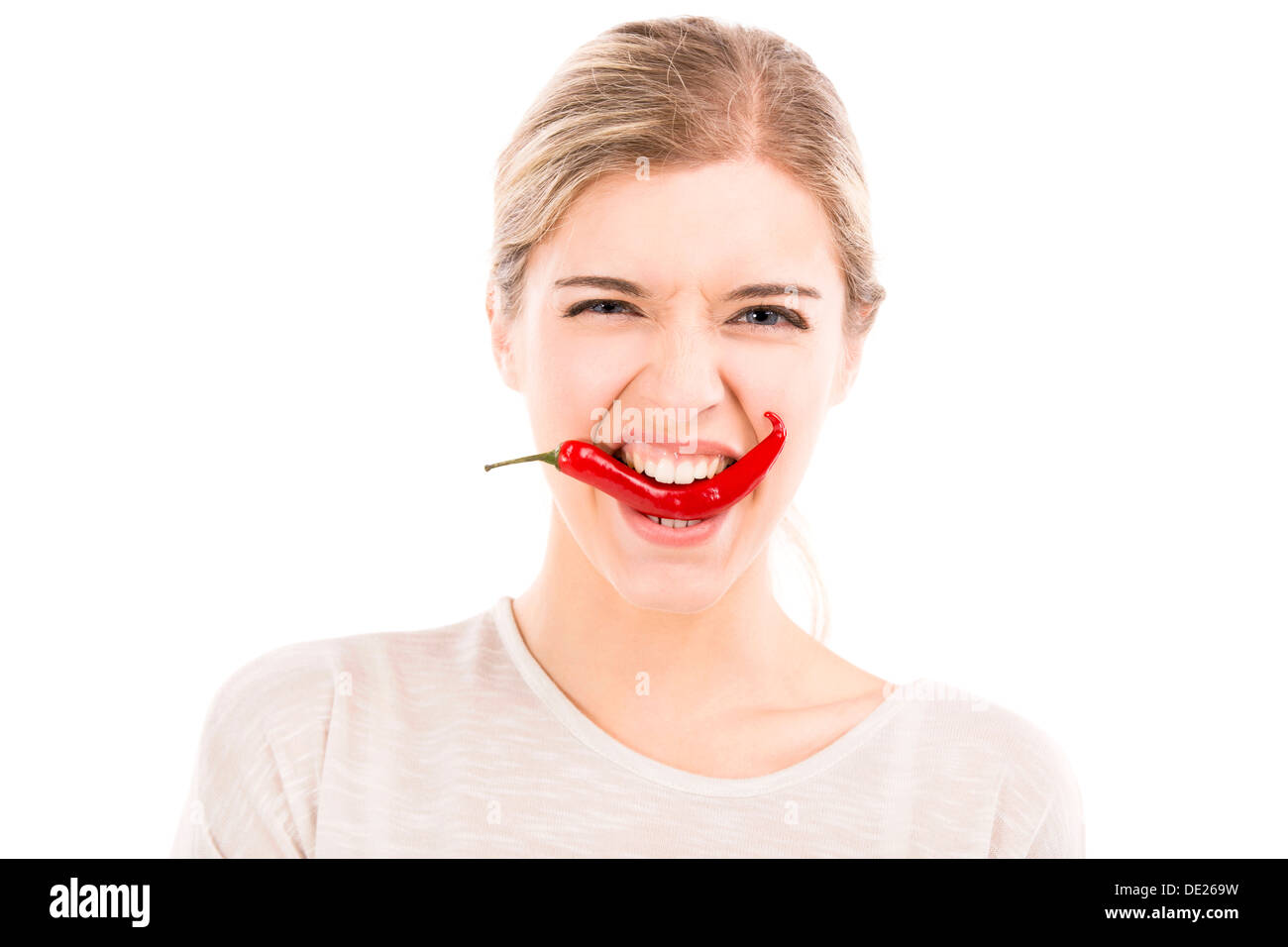 Bella ragazza di mordere un peperoncino rosso, isolato su uno sfondo bianco Foto Stock