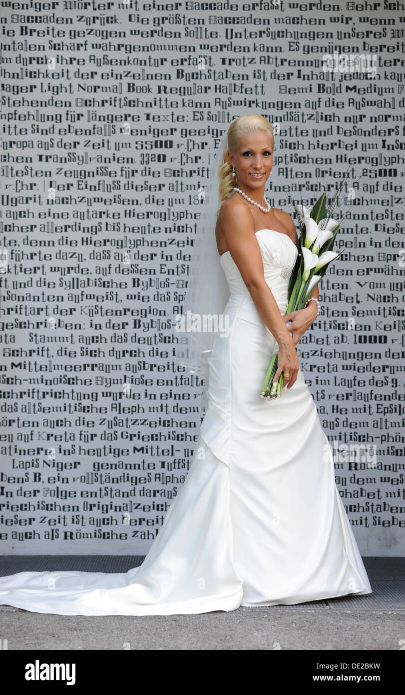 Matrimonio sposa con bouquet nuziale in piedi di fronte ad una parete con lettere Foto Stock