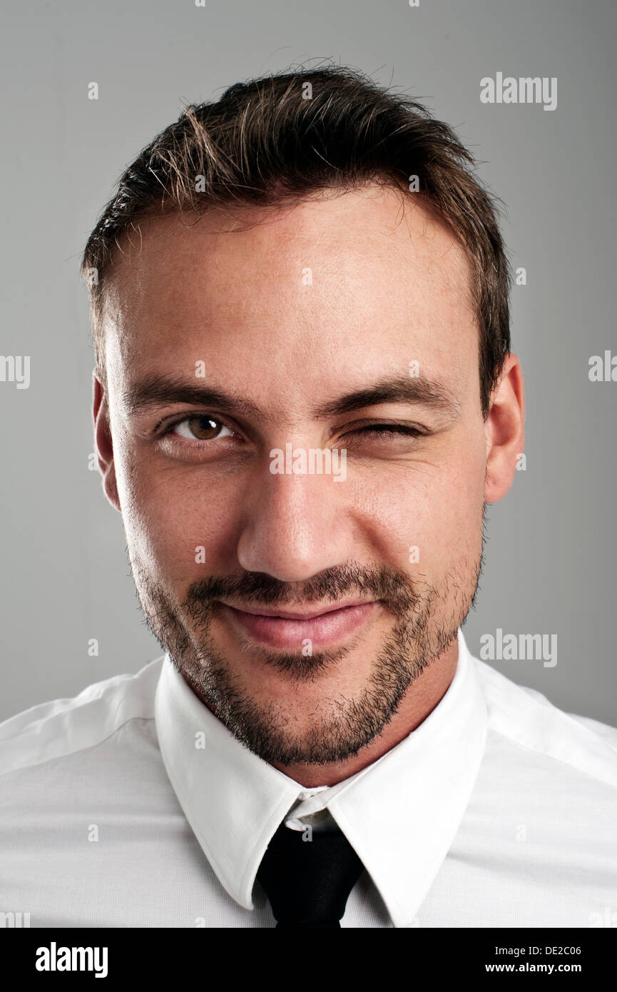 Giovane uomo che indossa una camicia e cravatta, lampeggio di un occhio, ritratto Foto Stock