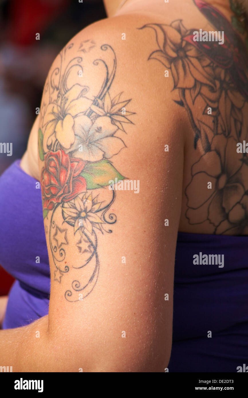 Fiori tattoo con Red Rose, giglio e hibiscus sulla donna e il braccio indietro Foto Stock