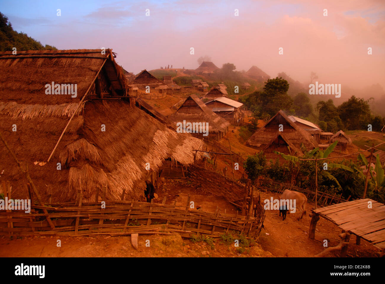 Misty tramonto sul villaggio con tetti di paglia appartenenti al Akha Nuquí gruppo etnico, divieto Peuyenxangkaw, Phongsali o Foto Stock