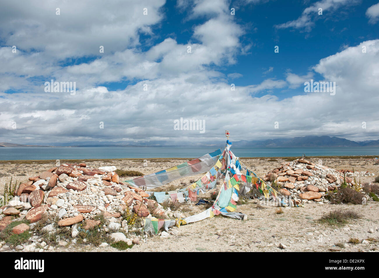 Buddismo tibetano, Mani pietre colorate e bandiere di preghiera con script tibetano, ex monastero di Gompa Nyengo sopra il lago Foto Stock