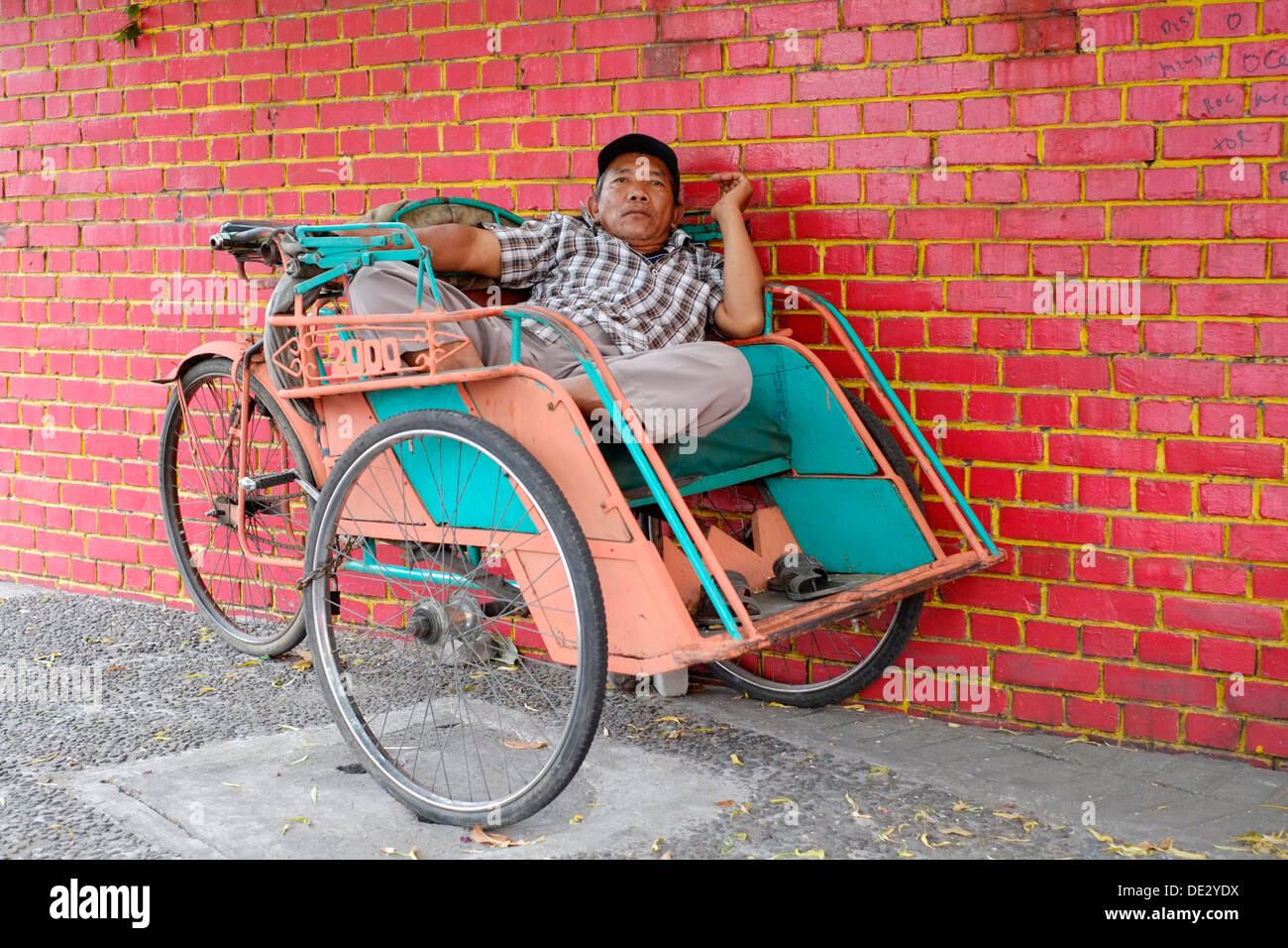 Local becak conducente appoggiati come egli attende i passeggeri kediri java indonesia Foto Stock