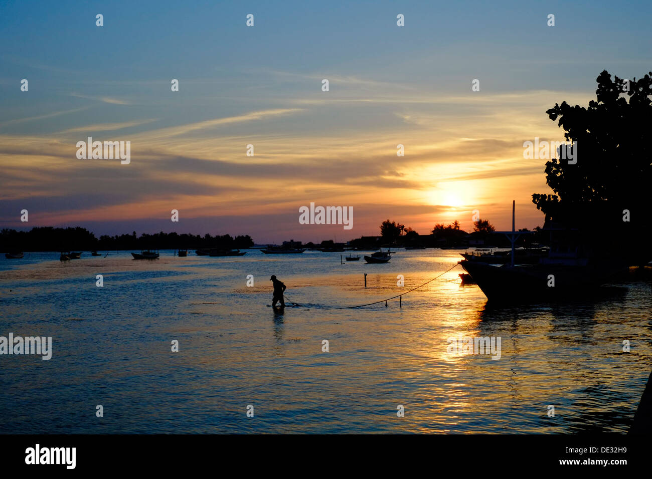 Pescatore si lega a sua barca come il sole tramonta oltre il porto di isola Karimunjawa indonesia Foto Stock