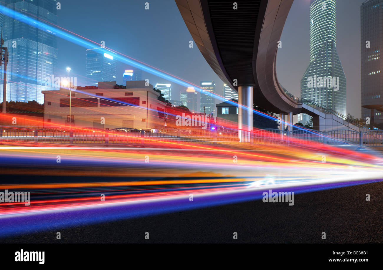 Ad alta velocità a veicoli luminose in percorsi su strade urbane sotto il cavalcavia di notte Foto Stock