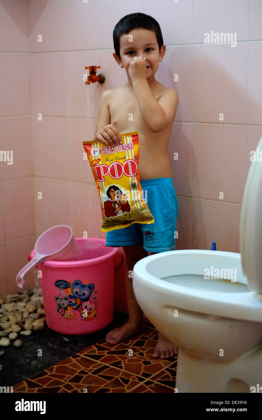 Ridere piccolo ragazzo locale in piedi in bagno da wc sacco di contenimento di tofu con il nome del marchio di poo Foto Stock