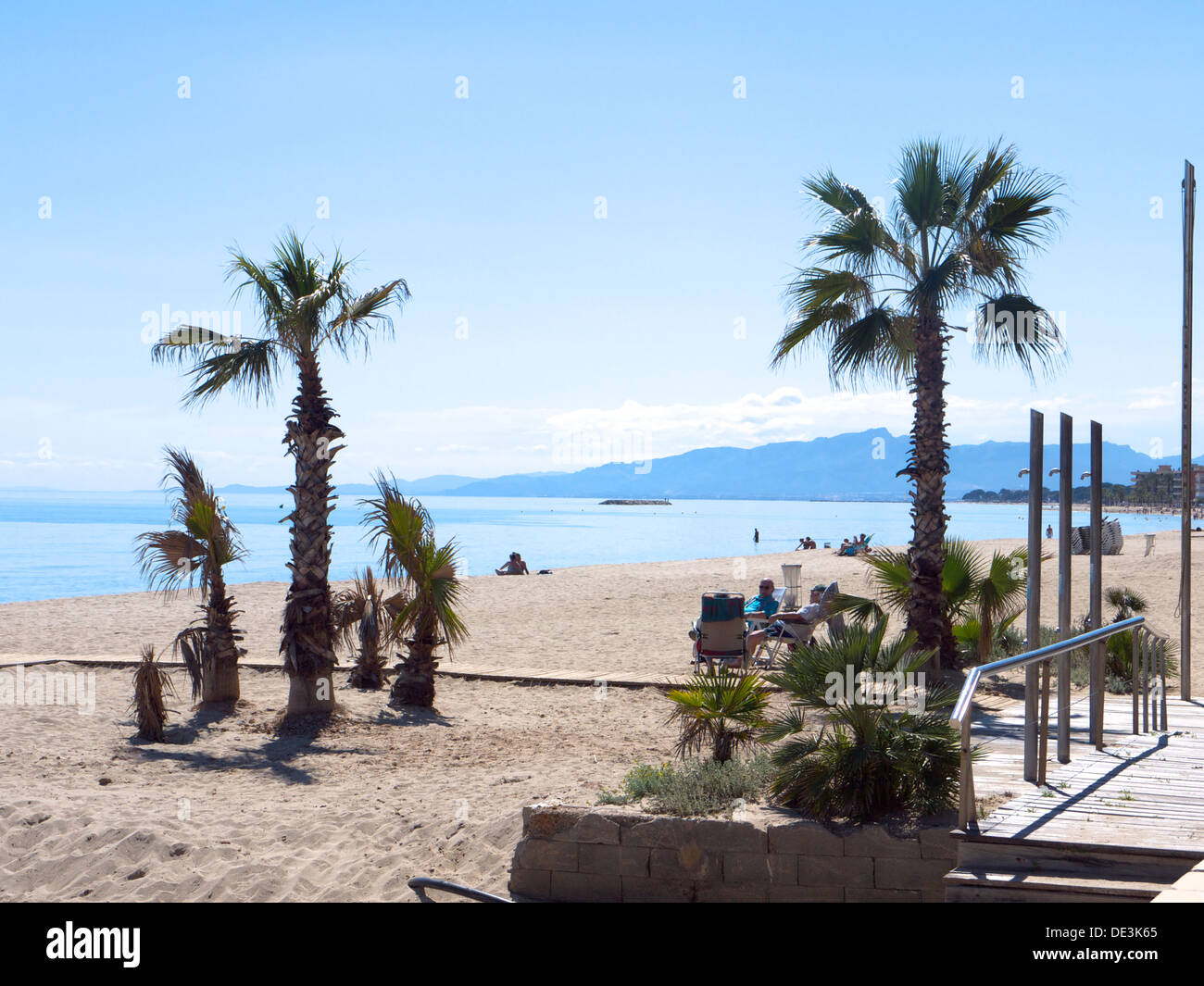 Le palme sulla spiaggia con il mare e le montagne sullo sfondo Foto Stock