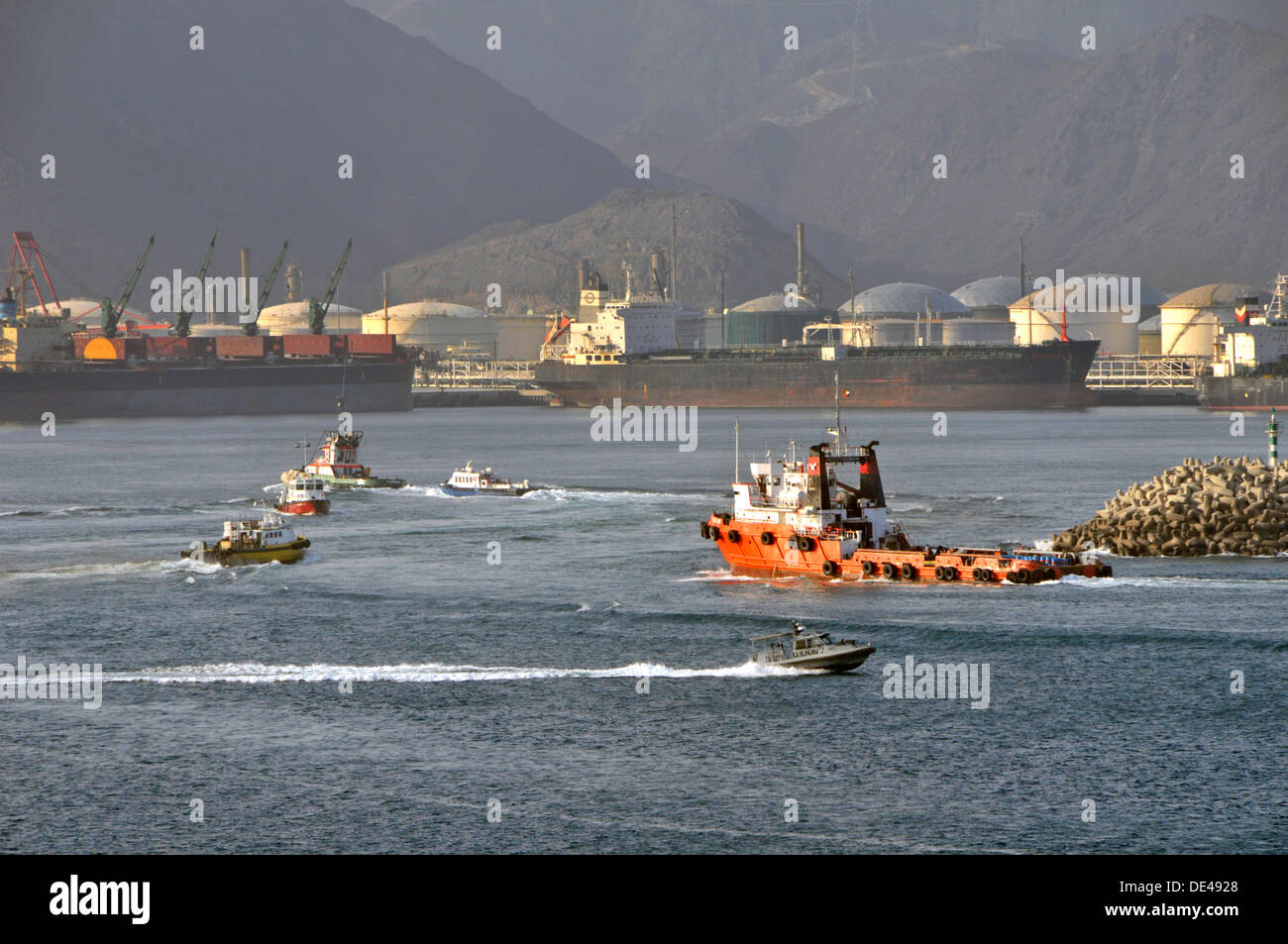 Occupato di attività del porto al Fujairah bunkeraggio porto Golfo di Oman con petroliera e serbatoi di stoccaggio al di là (nota US Navy patrol) Foto Stock