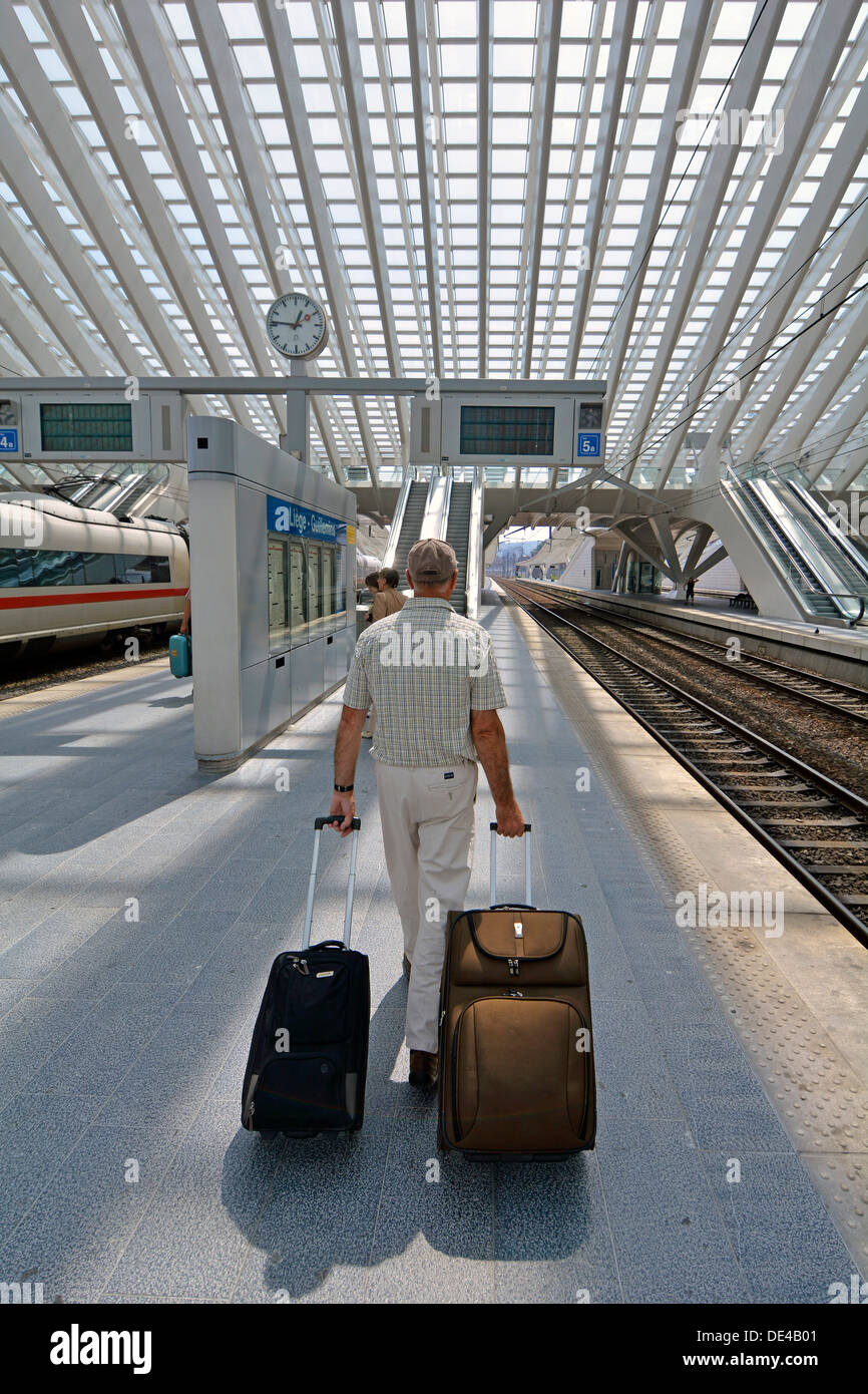 Modello di rilascio senior uomo passeggero ferroviario persona che cammina con la valigia bagaglio sulla stazione ferroviaria piattaforma di Liegi in Belgio UE moderna costruzione tetto di vetro Foto Stock