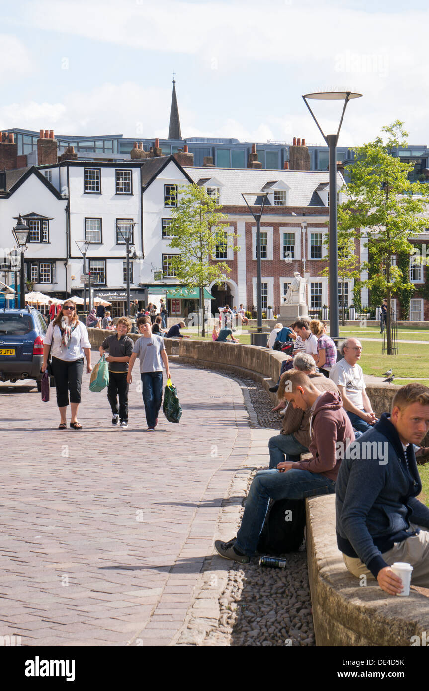 La gente seduta su una parete godendo un sole estivo, Cattedrale verde, Exeter Devon, Inghilterra, Regno Unito Foto Stock
