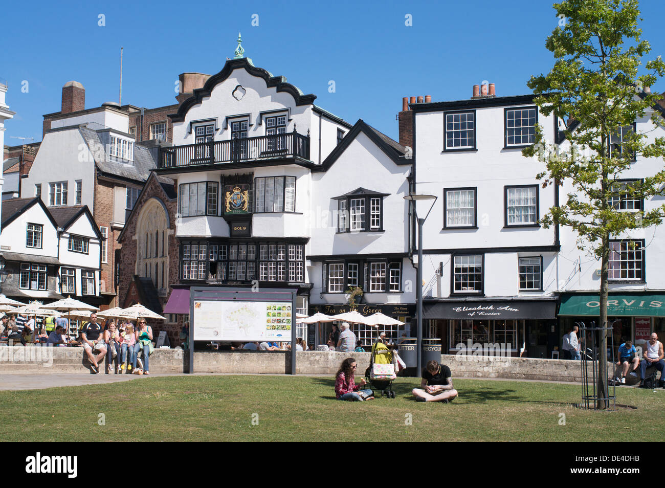 La gente seduta al sole vicino Cattedrale, Exeter Devon, Inghilterra, Regno Unito Foto Stock