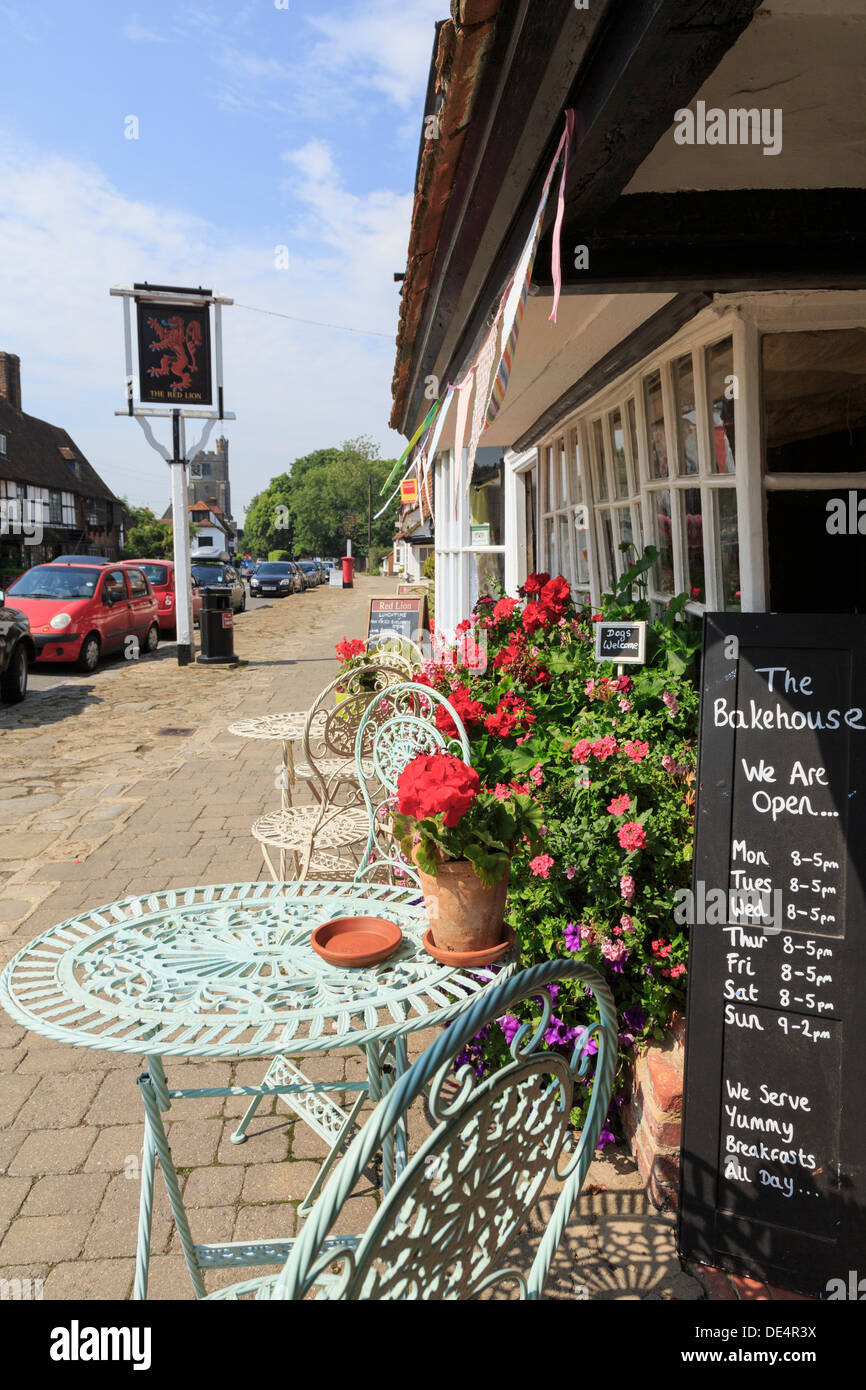 Sedie e tavoli e fiori al di fuori il Bakehouse Cafè teashop sulla strada principale in Biddenden, Kent, Inghilterra, Regno Unito, Gran Bretagna Foto Stock