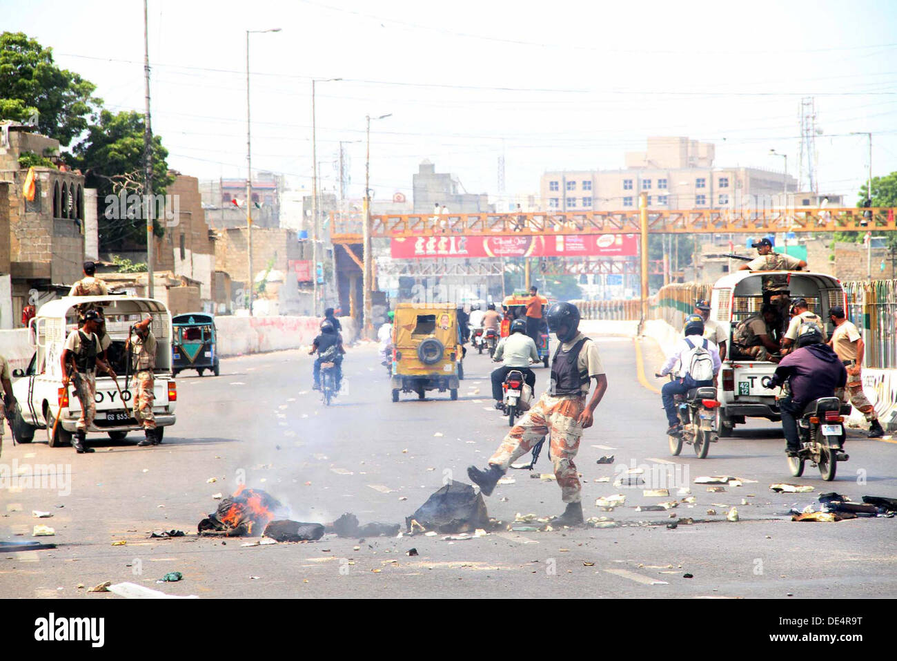 La sicurezza dei funzionari sono la rimozione di ostacoli di masterizzazione che si è bloccato in strada come il Metropolitan è osservando la protesta senza preavviso giorno dopo la detenzione di MQM ex membro del gruppo del Sindh, Nadeem Hashmi dalla polizia, a corridoio III a Karachi il Mercoledì, 11 settembre 2013. Foto Stock