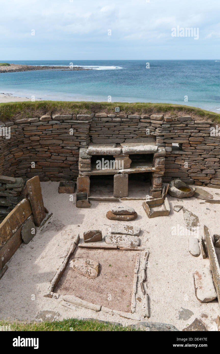 Casa 1 a Skara Brae villaggio neolitico sulla terraferma Orkney con la baia di Skaill in background. Foto Stock