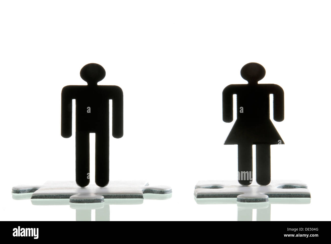 Figura maschile e una figura femminile in piedi sul puzzle pezzi, immagine simbolica per la ricerca di un partner Foto Stock