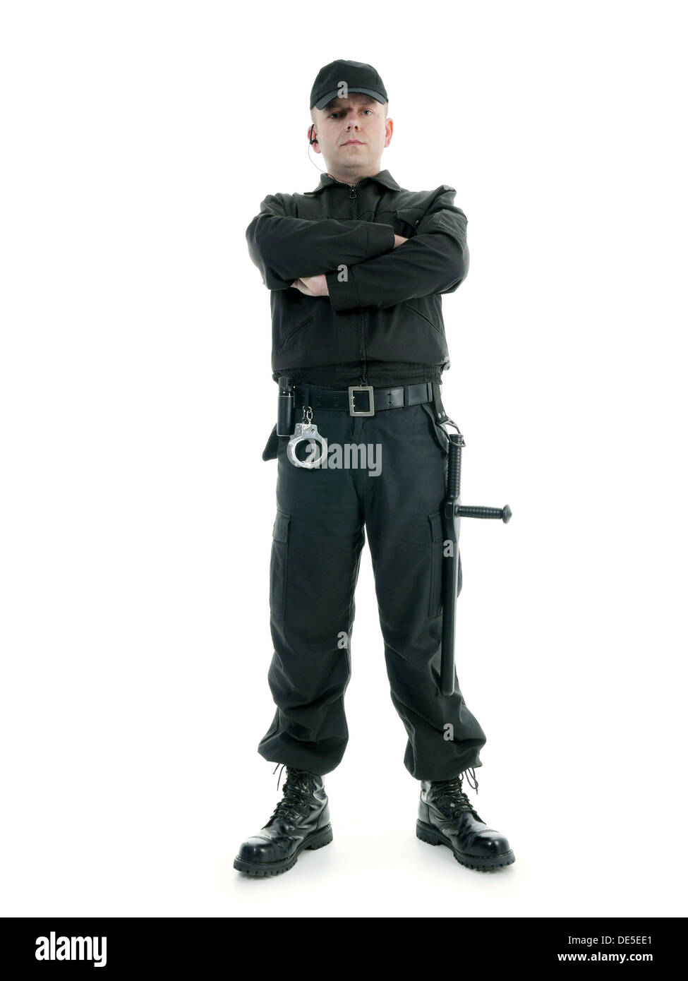 Uomo di sicurezza usura uniforme nero dotato di club di polizia e manette tranquillamente in piedi con le braccia incrociate, shot su bianco Foto Stock