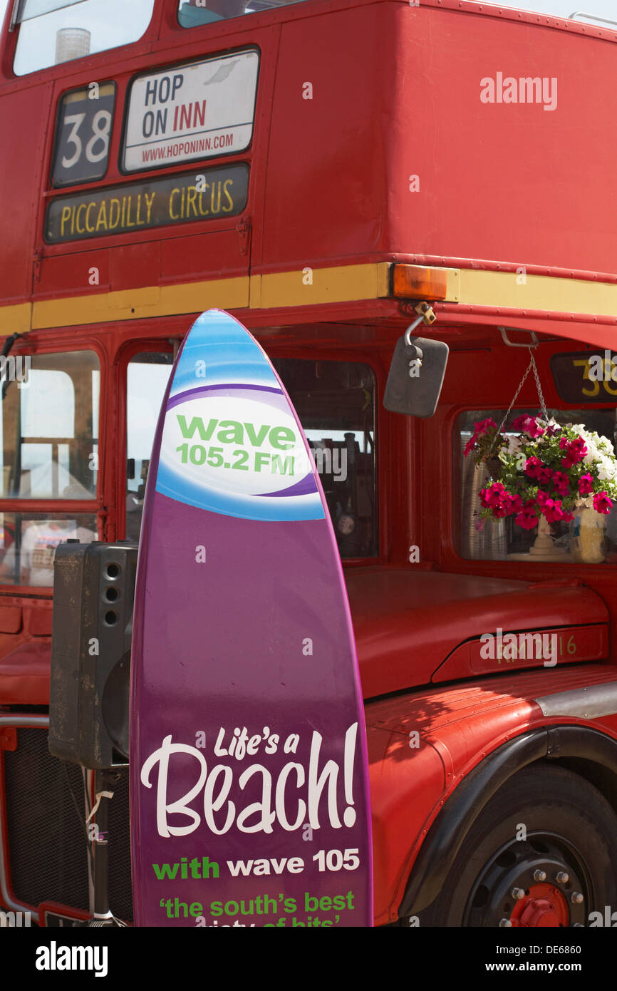 Hop on Inn red double decker bus numero 38 con Wave 105.2 FM la vita è una spiaggia con Wave 105 segno a Bournemouth Foto Stock
