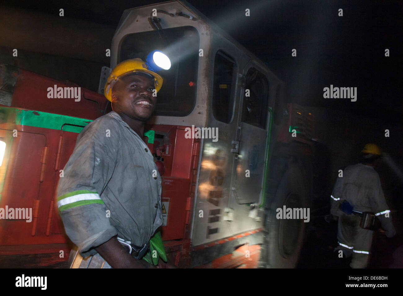 Un minatore con un autocarro pesante utilizzato per carrello di minerale grezzo alla superficie in un sotterraneo miniera d'oro Foto Stock