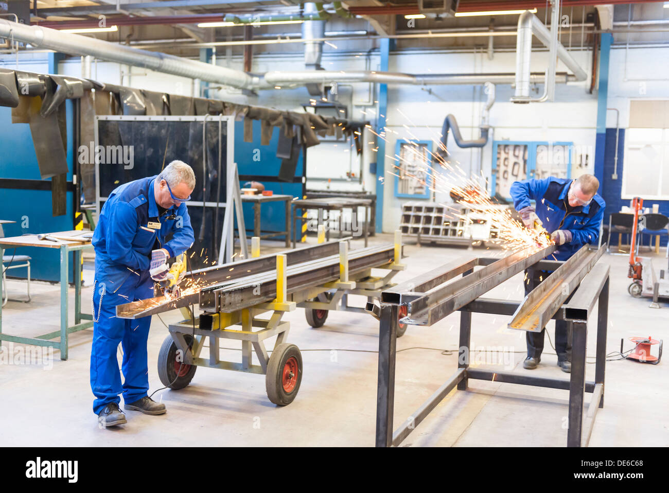 In un ambiente industriale, due lavoratori craft e affinare le estrusioni in metallo per un progetto di costruzione. Foto Stock