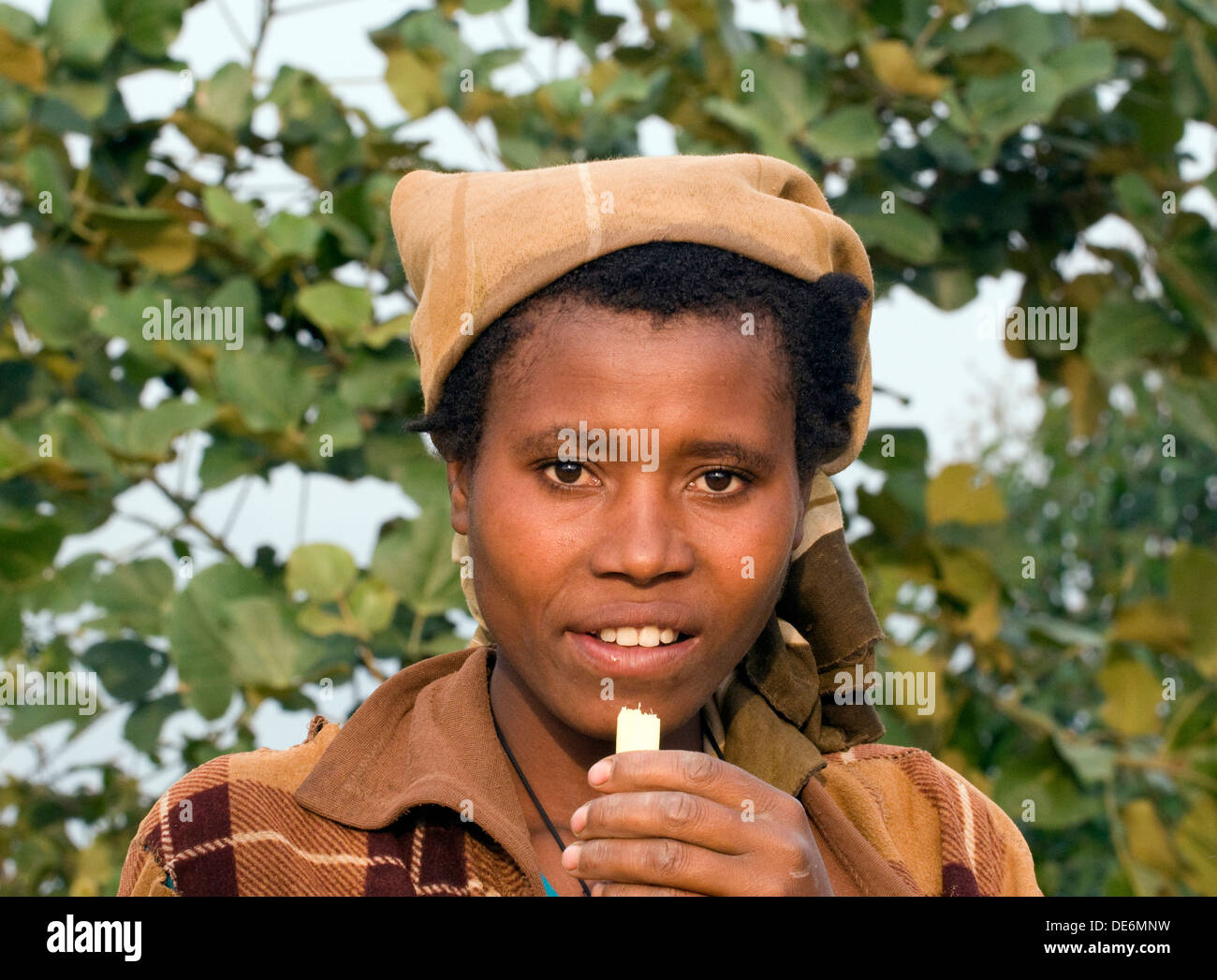 Bella donna ruandese con la canna da zucchero in mano in vista di active Virunga montagne vulcaniche vicino al lago Burera Ruanda centrale Foto Stock