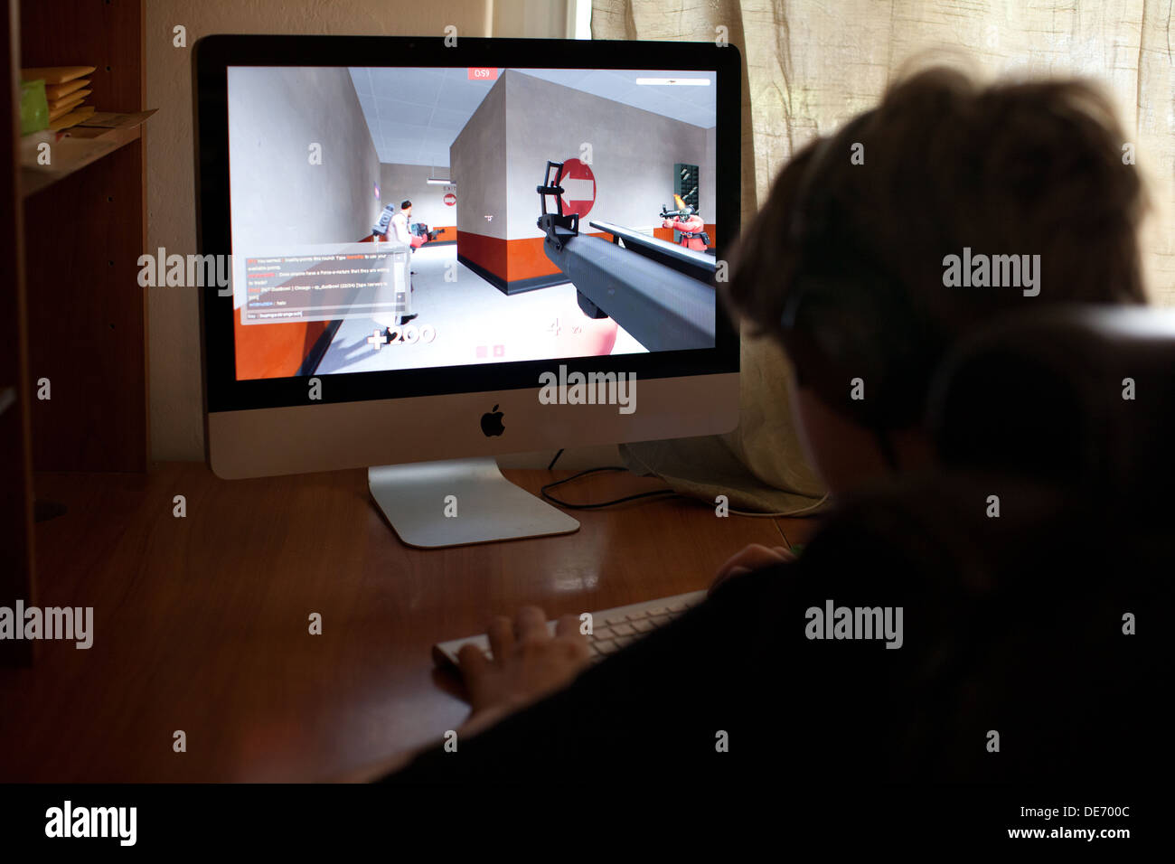 Tredici anni di vecchio ragazzo la riproduzione di video gioco Team Fortress sul computer di casa, il gioco online con gli amici. Foto Stock