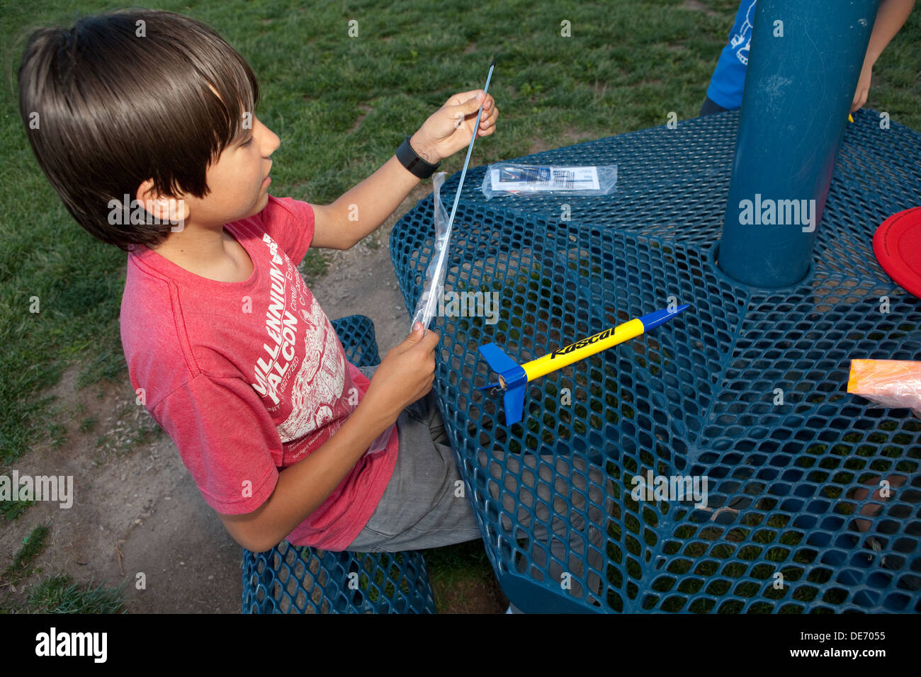 Dodici anni ragazzo ispanico assemblando un modello impostato a razzo a sparare in cielo in un parco. Foto Stock