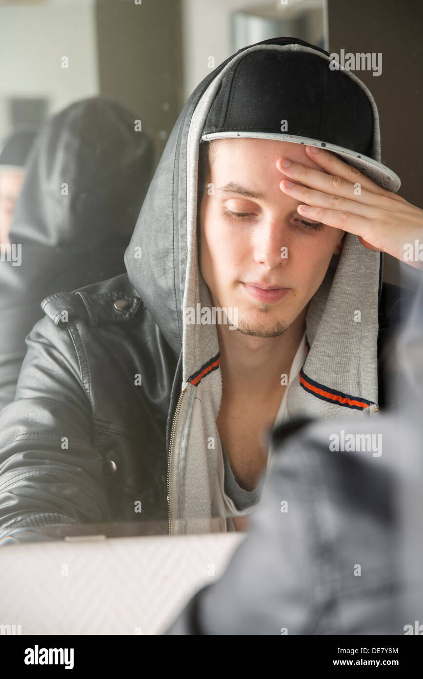 Preoccupante e ha sottolineato giovane con atteggiamento fresco seduto di fronte a specchio Foto Stock