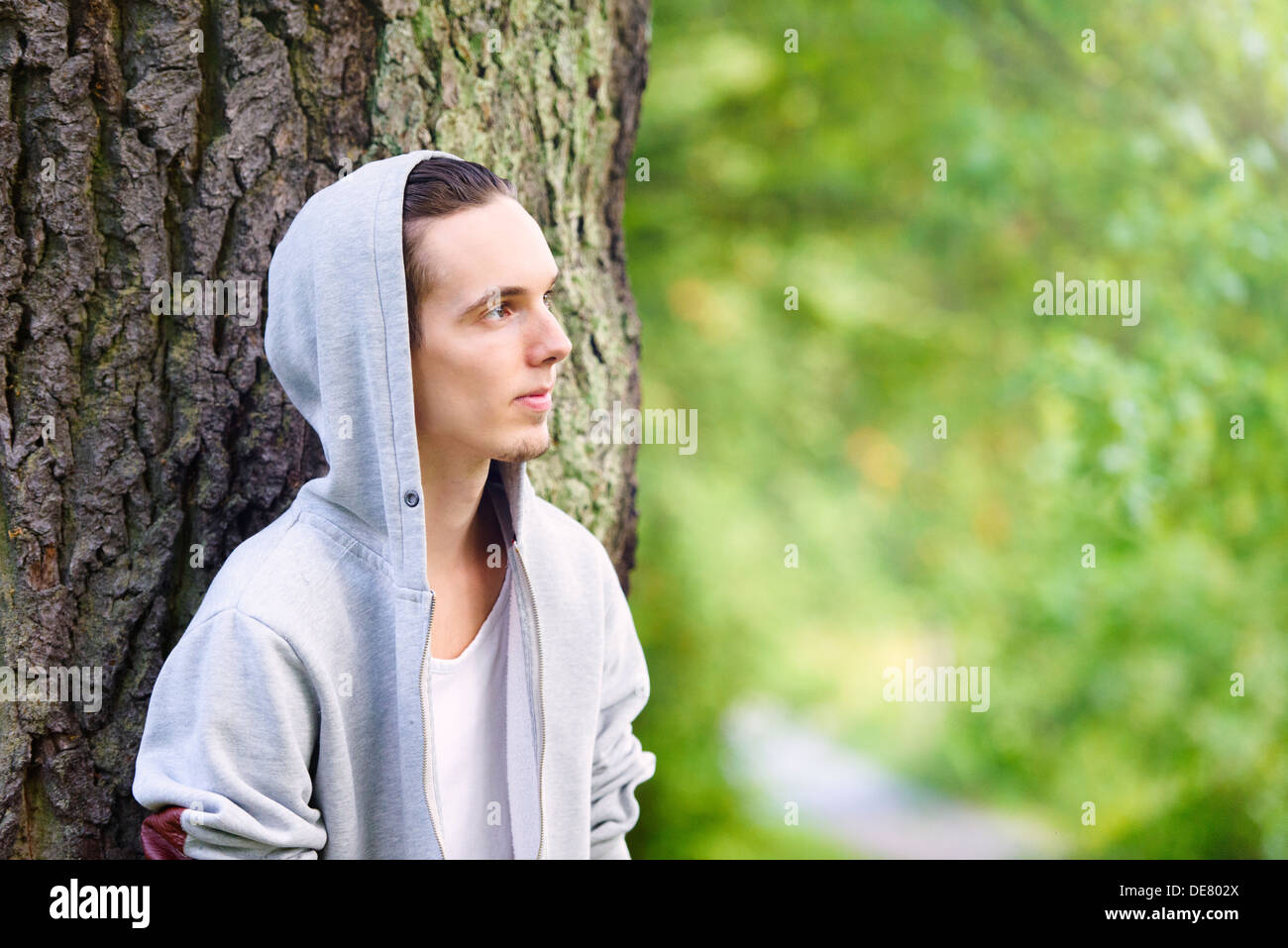 Giovane uomo in piedi da sé e pensando a una foresta Foto Stock