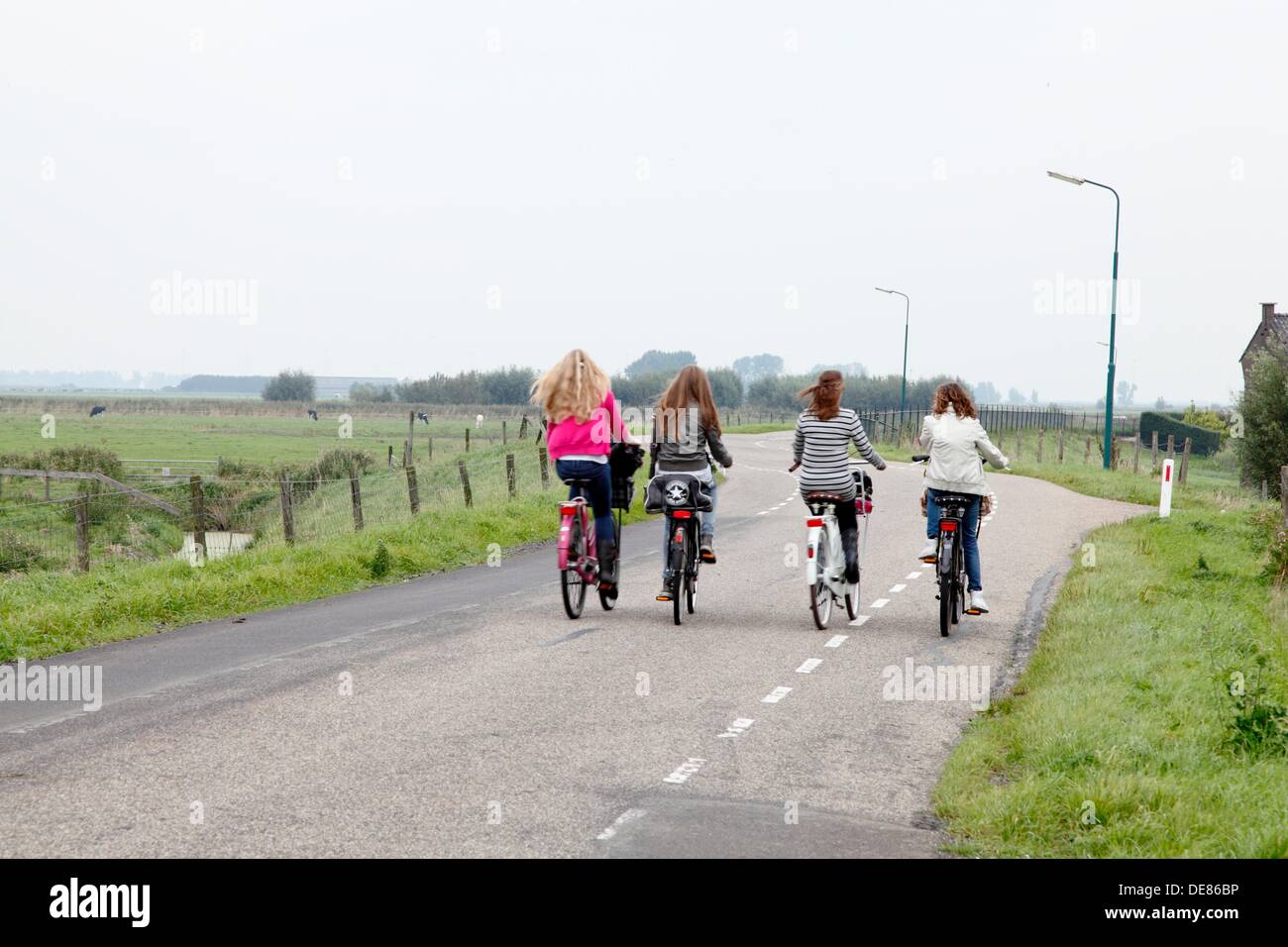 Ragazze bike affiancati sulla diga, tornando a casa dopo la scuola, Paesi Bassi Foto Stock