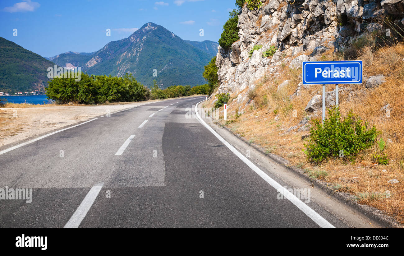 Mountain strada asfaltata e cartello blu con Perast nome della città in Montenegro Foto Stock