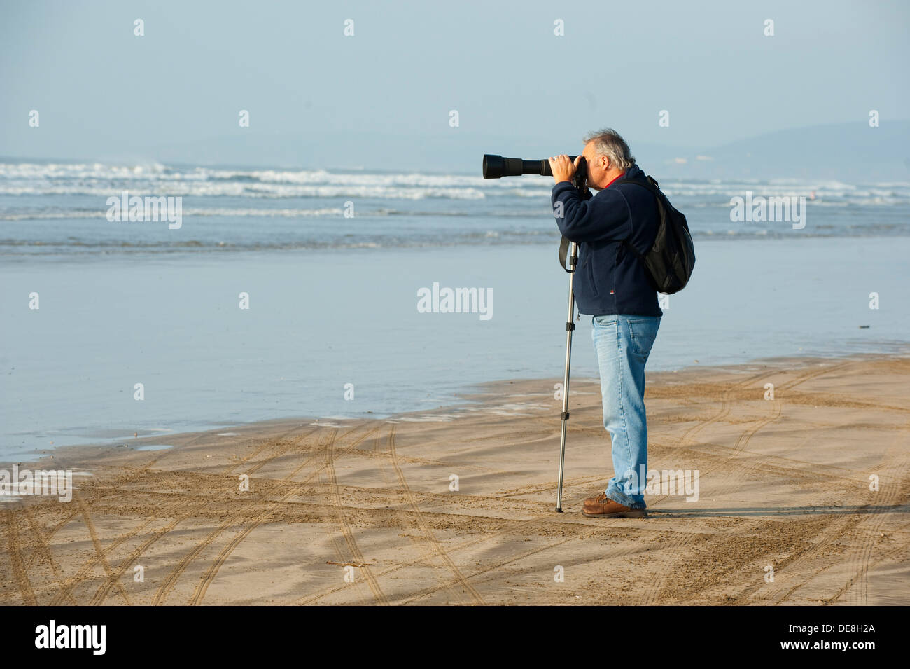 Fotografo di scattare una foto utilizzando un monopiede sulla spiaggia di Condino Devon, Inghilterra, Regno Unito Foto Stock