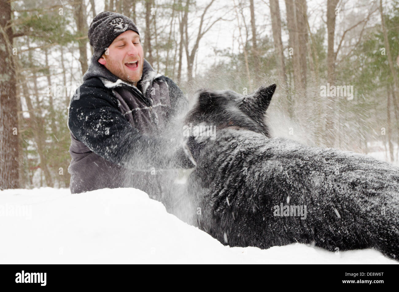 Un uomo e un cane giocare nella neve durante una bufera di neve. Foto Stock