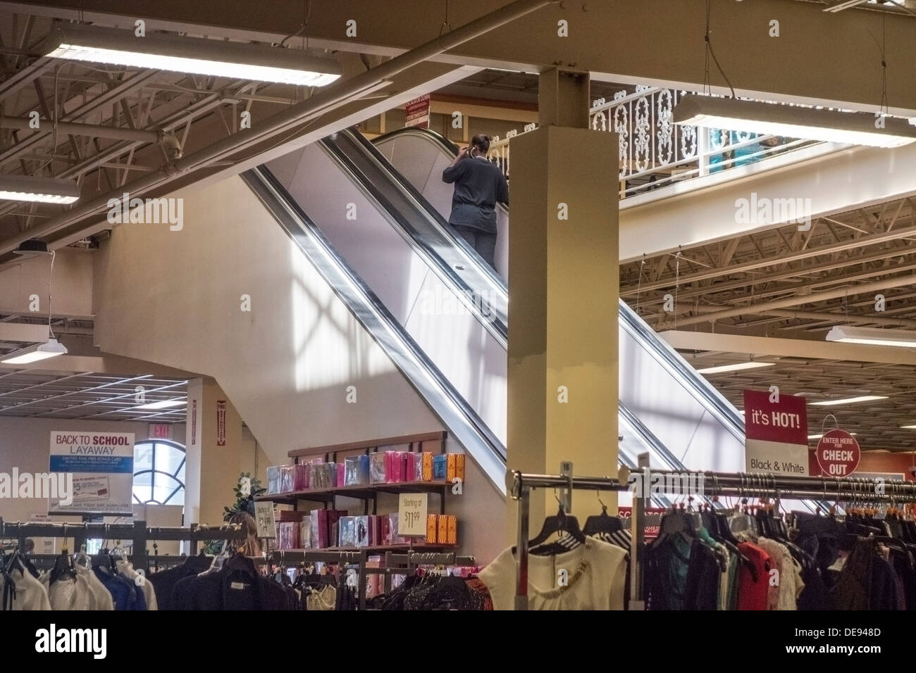 All'interno di un dipartimento di sconto negozio con cremagliere di vestiti e di una donna in sella alla scala mobile. Oklahoma City, Oklahoma, Stati Uniti d'America. Foto Stock