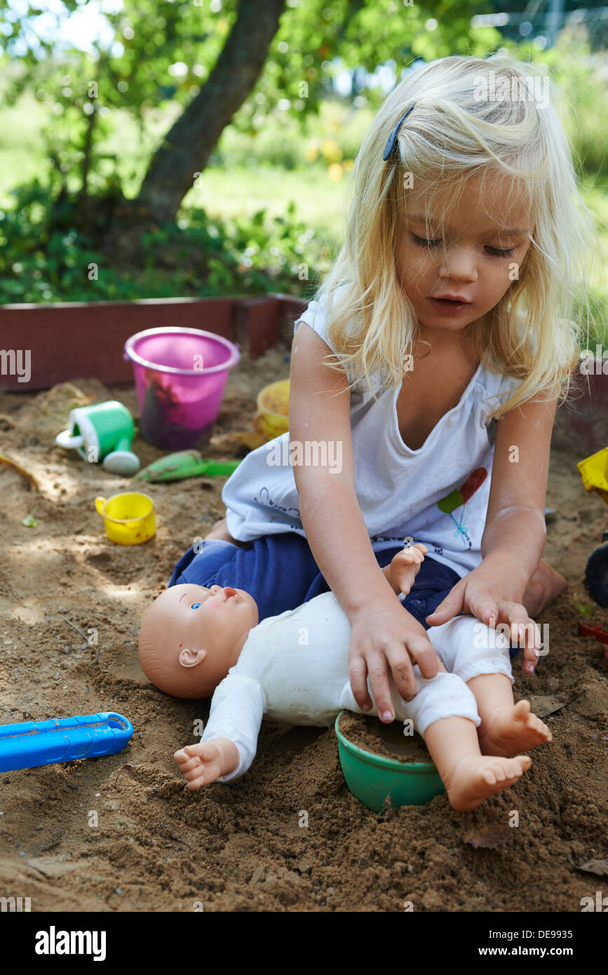 Bimba bionda giocando nella buca di sabbia al giardino estivo Foto Stock