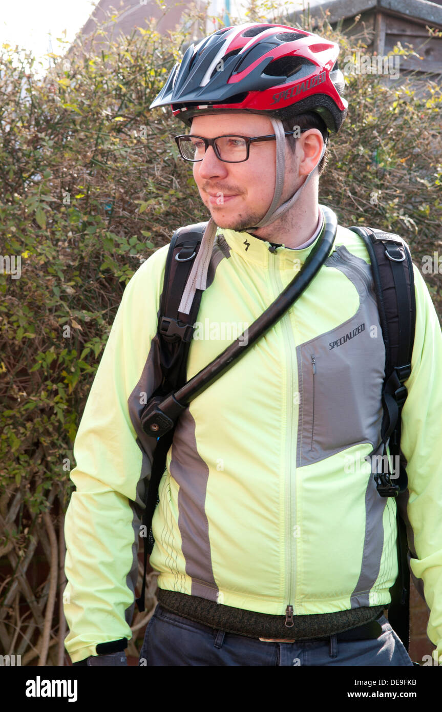 Ritratto di un uomo che indossa abiti in bicicletta, casco, zaino e occhiali sorridente Foto Stock