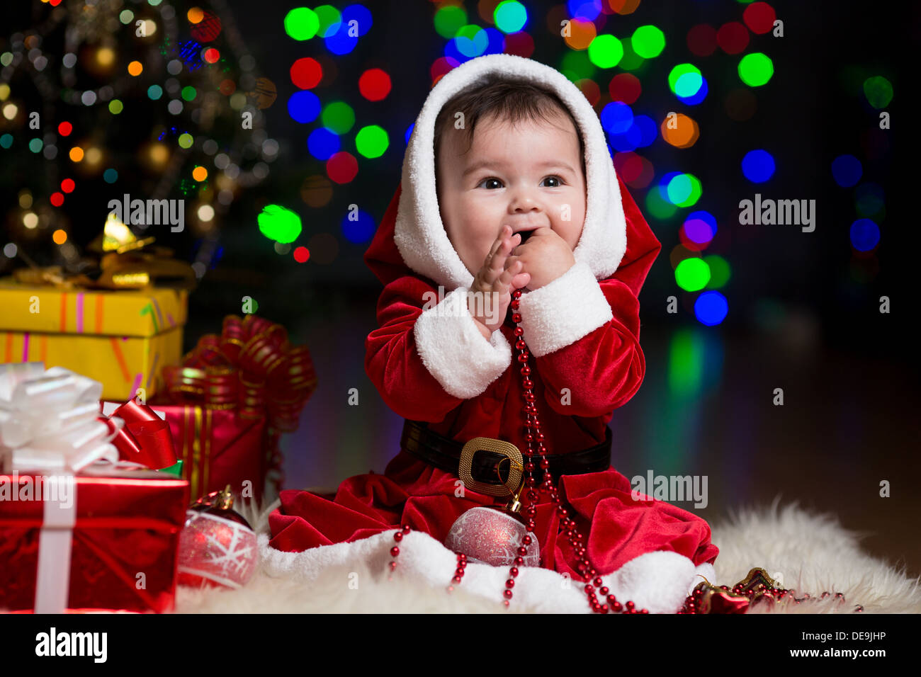 Kid ragazza vestita come Santa Claus nei pressi di albero di Natale con doni Foto Stock