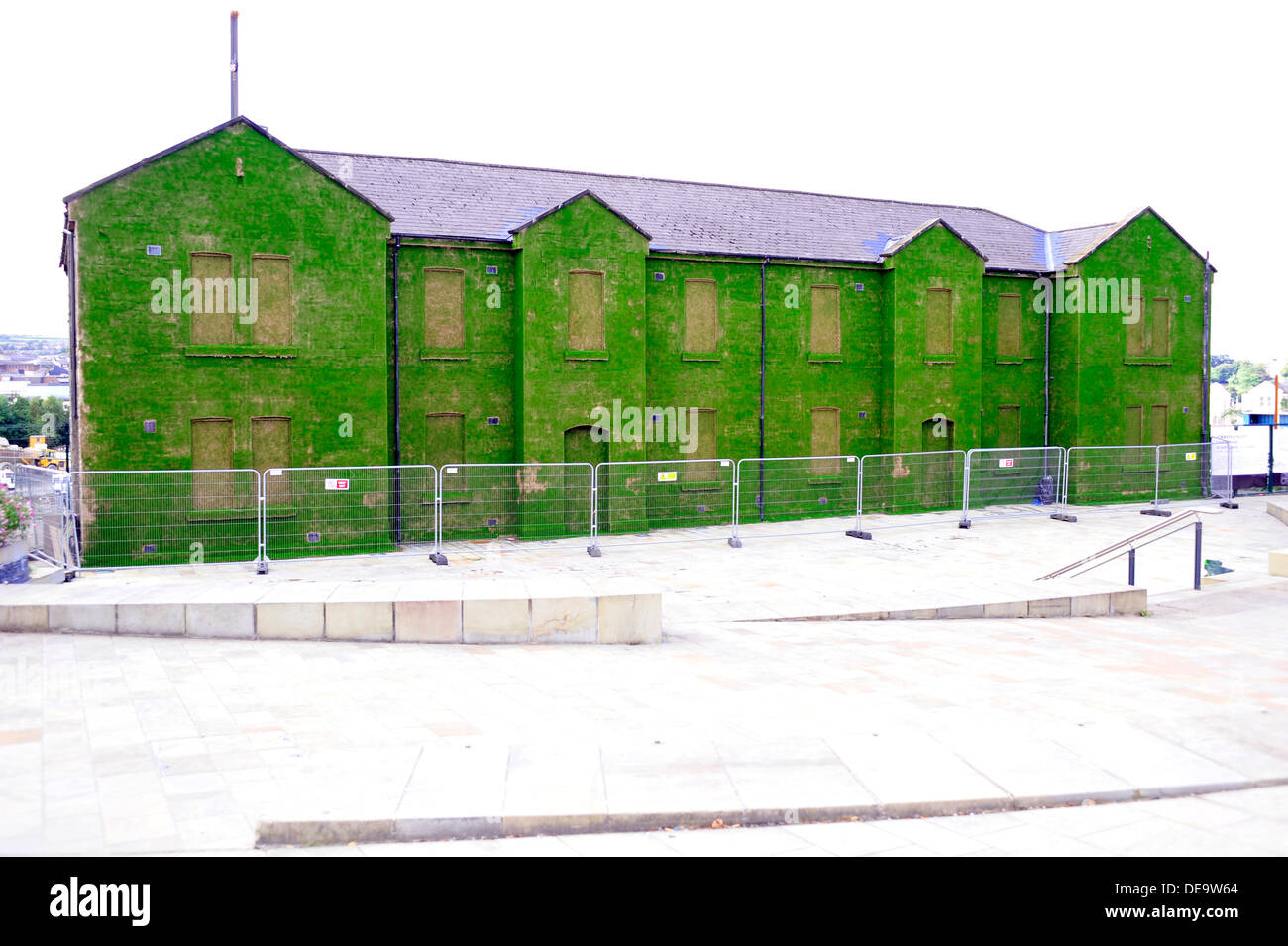 Ebrington Square, Derry, Londonderry, Irlanda del Nord, Regno Unito, 14 Sett. 2013. Un edificio storico e ex esercito britannico sposato trimestri è stata trasformata in una temporanea installazione d arte. Il dark facade di Cunningham edificio in Piazza Ebrington è stato ricoperto da milioni di sementi di erba da artista Dan Harvey e il suo partner Heather Ackroyd al numero. L'installazione, parte della città del Regno Unito la cultura del progetto, è aperta al pubblico dal 15 settembre al 27 ottobre 2013. Credito: George Sweeney / Alamy Live News. Credito: George Sweeney / Alamy Live News Foto Stock