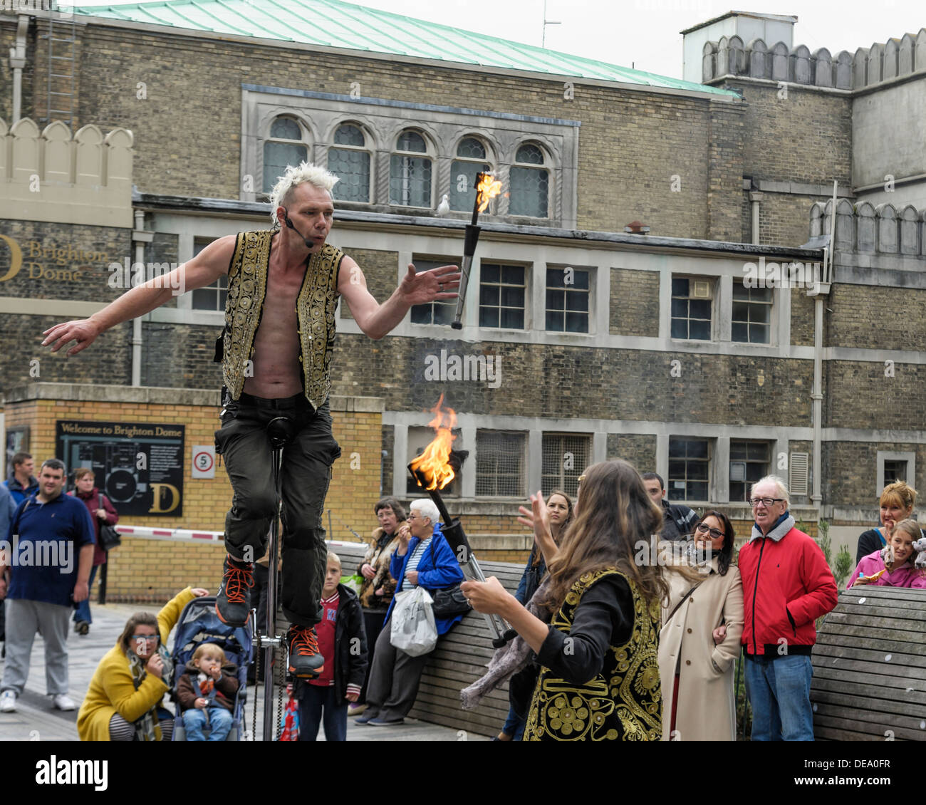 Brighton, Regno Unito, 14/09/2013 : un esecutore di strada su un alto monociclo catture flaming juggling bastoni. Foto di Julie Edwards Foto Stock