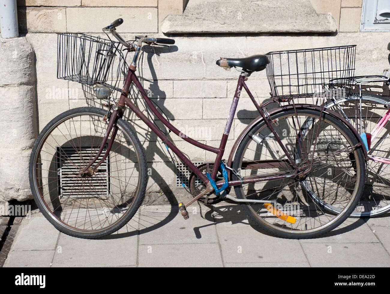 Una vecchia bicicletta appoggiata contro un muro di pietra con cesti Foto Stock