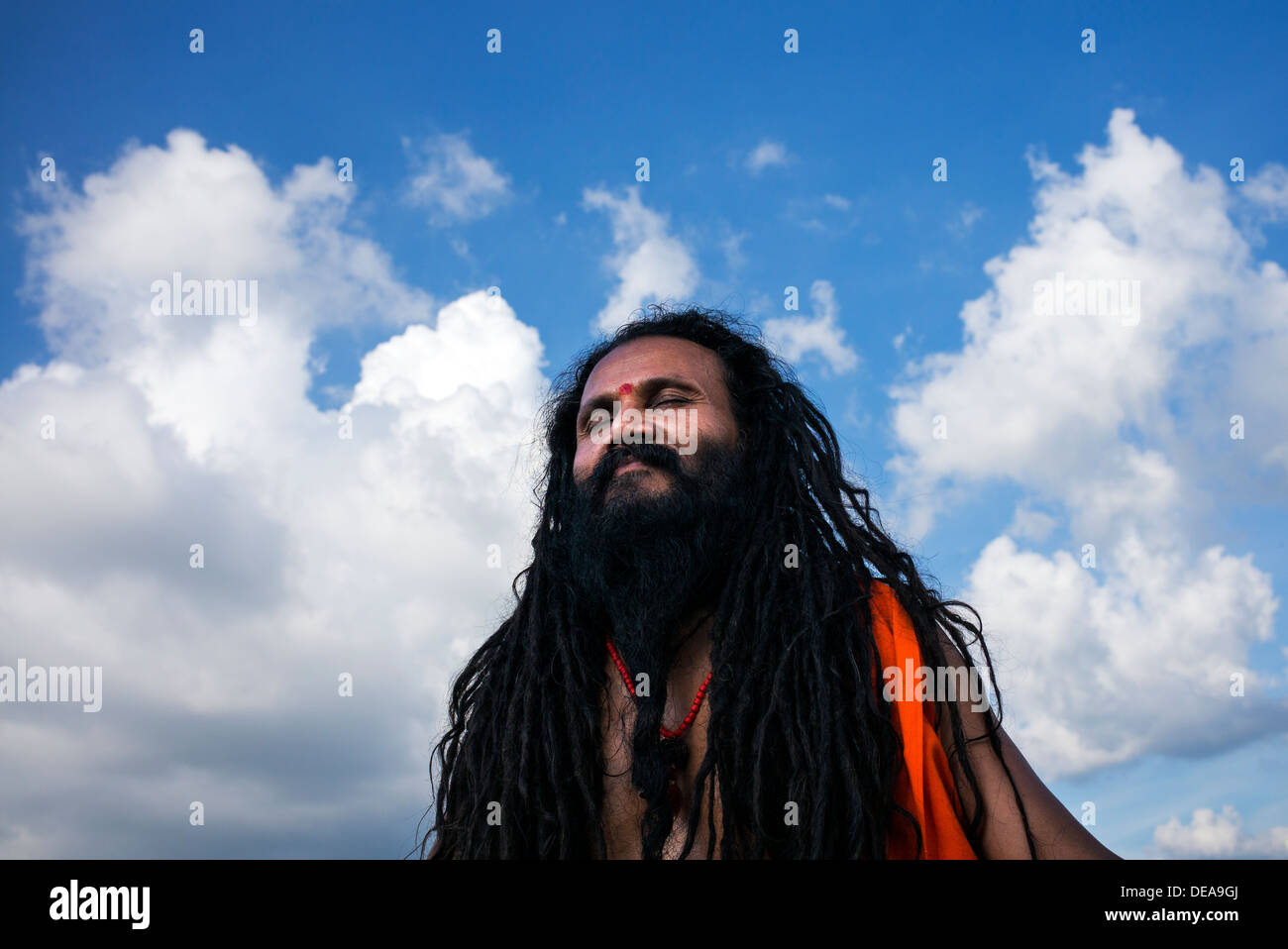Sadhu indiano in meditazione contro un blu cielo nuvoloso. India Foto Stock