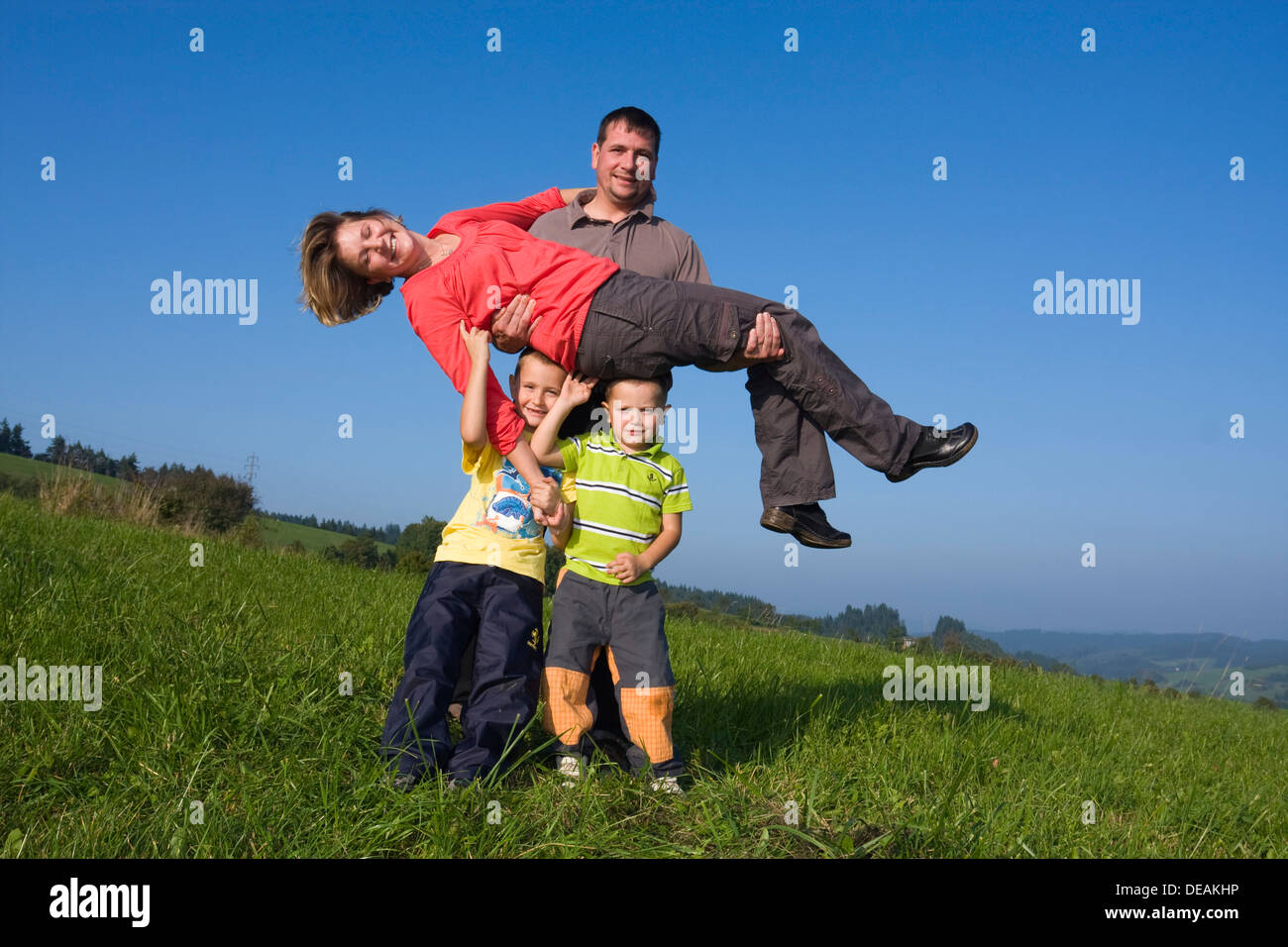 Famiglia, padre, 36 anni, madre, 30 anni, i bambini di 6 e 4 anni, giocando in un prato Foto Stock