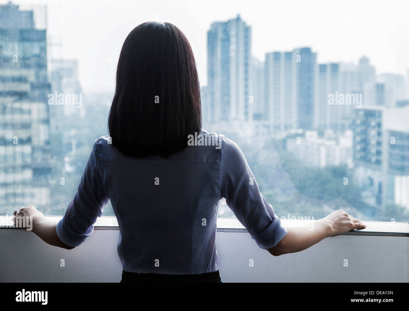 Vista posteriore di una imprenditrice guardando fuori dalla finestra al paesaggio urbano a Pechino in Cina Foto Stock