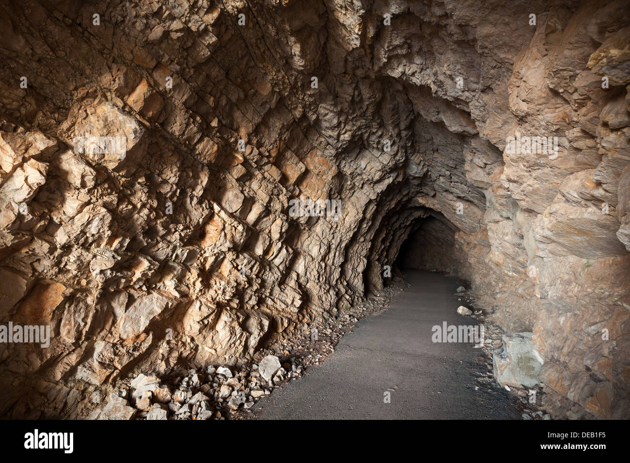 Strada asfaltata passa attraverso la grotta al buio Foto Stock