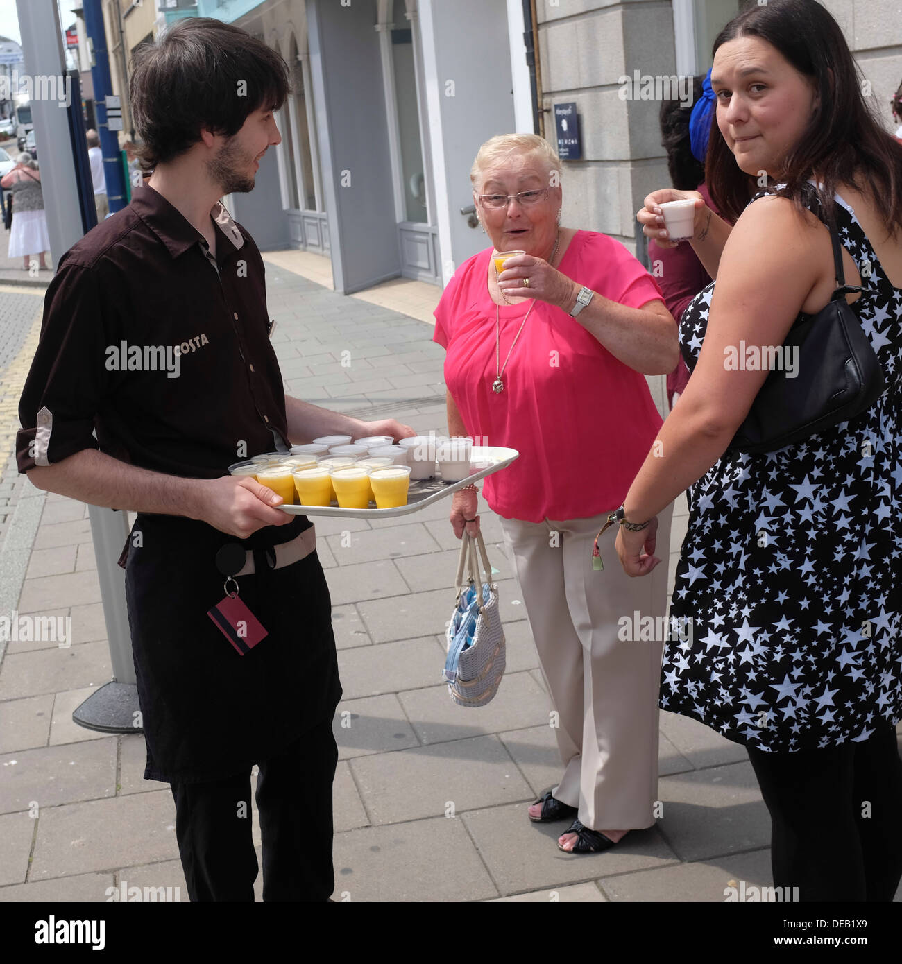 Un giovane uomo che offre campioni gratuiti di Costa freddo bevande frutta sulla strada, in una calda giornata estiva 2013 REGNO UNITO Foto Stock